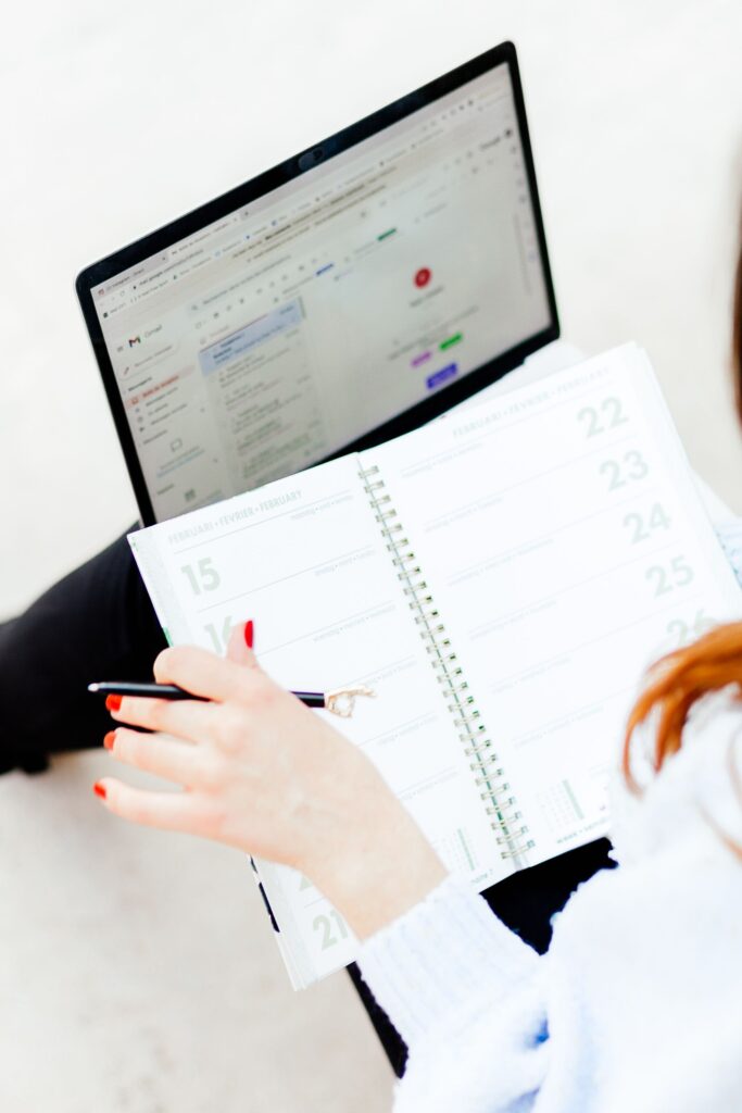 pexels photo 14465804 14465804 Woman using laptop and notebook for work organization and schedule planning indoors.